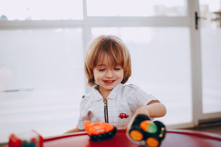 Joyful child playing with toy cars by a window, displaying happiness and creativity.